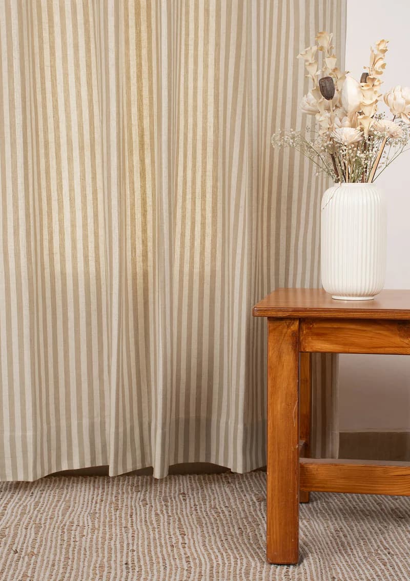 Olive and beige striped cotton curtain beside a wooden side table
