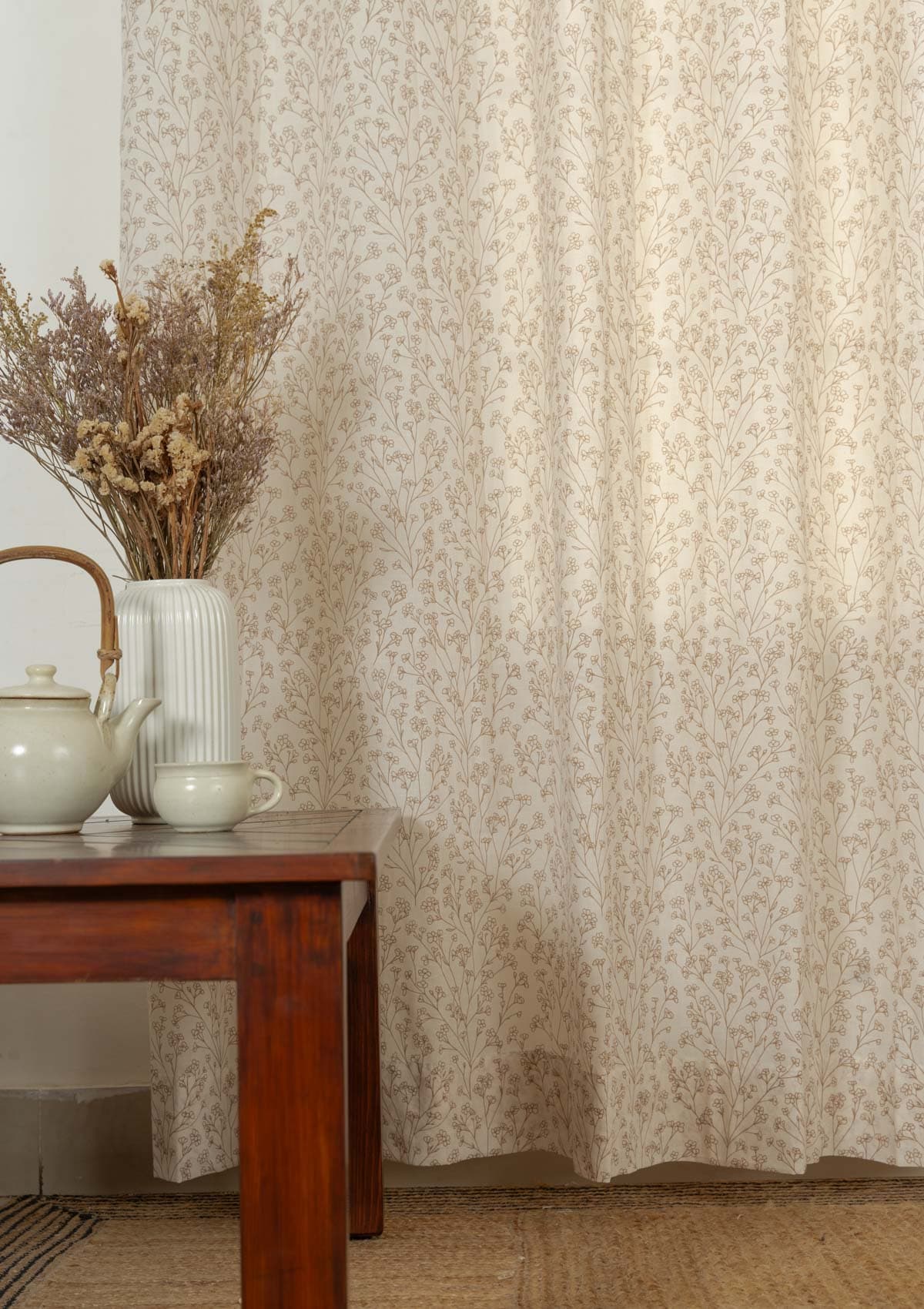 Beige cotton floral sheer curtain filtering soft daylight in a warm living room